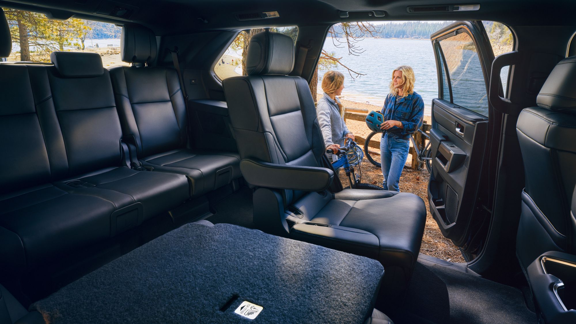 black Toyota Sequoia interior, looking out onto a lake with two people standing nearby