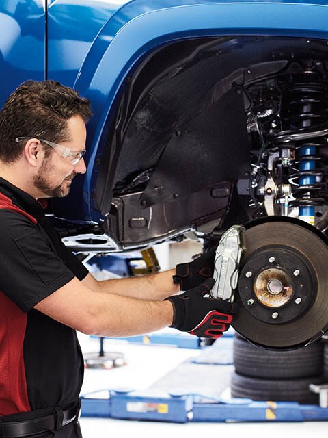 Toyota Brake Replacement at Klamath Falls Toyota A Toyota service technician standing next to a vehicle replacing the brake pads.