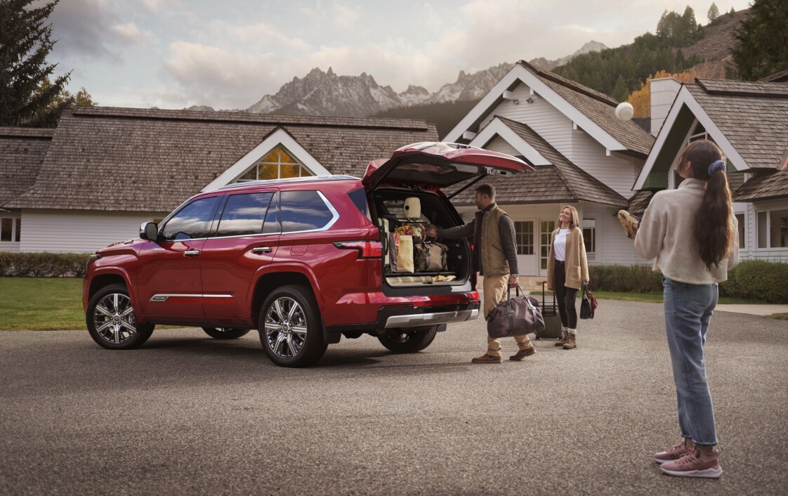 New 2022 Toyota Sequoia Cargo Space.png red Toyota Sequoia SUV parked next to a home, with the trunk open