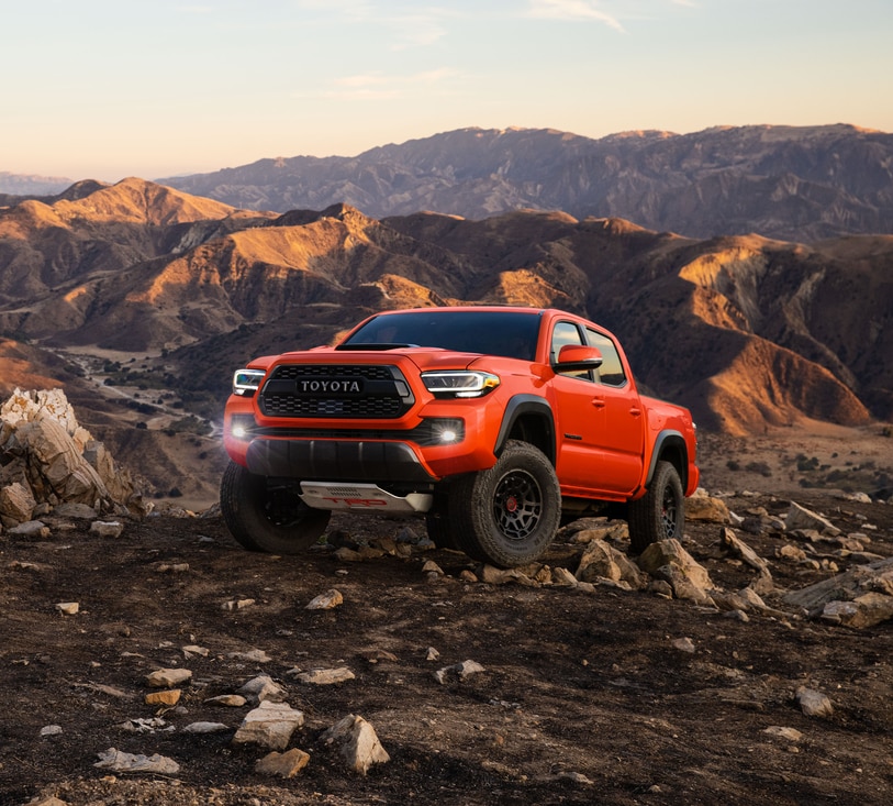 orange Toyota Tacoma truck parked on a sharp, rocky trail