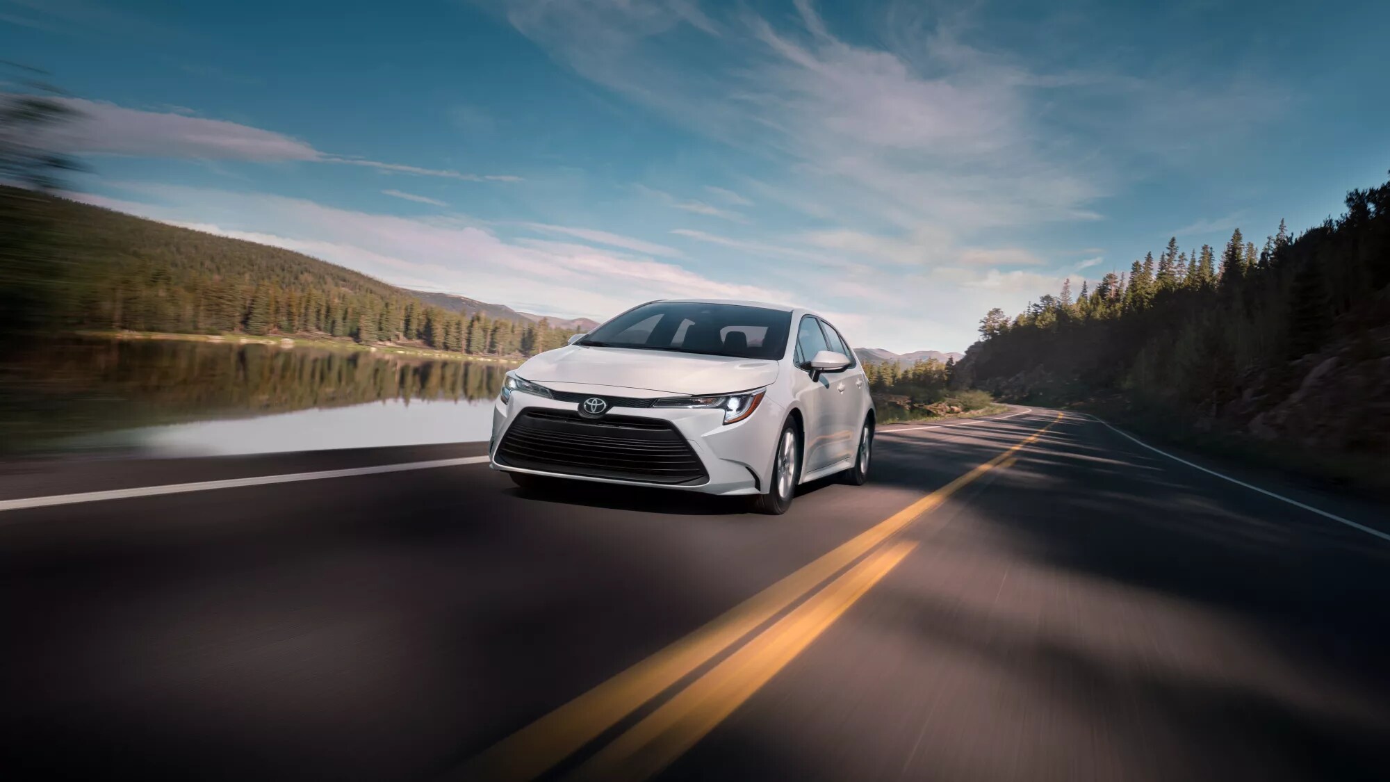 white Toyota Corolla driving on a road next to a river