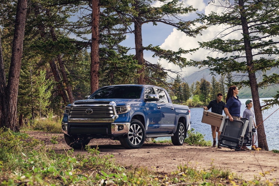 2021-Toyota-Tundra-Limited-CrewCab-StandardBed-Truck-L01.png blue Toyota Tundra parked under a tree, with a family walking towards the water with fishing gear