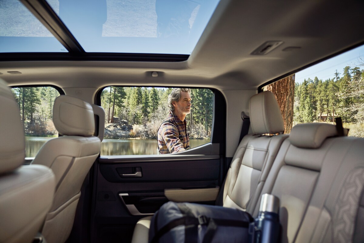 2022-Toyota-Tundra-1794-CrewCab-Truck-I02.png man getting into the back seat of his Toyota Tundra truck to get some camping gear