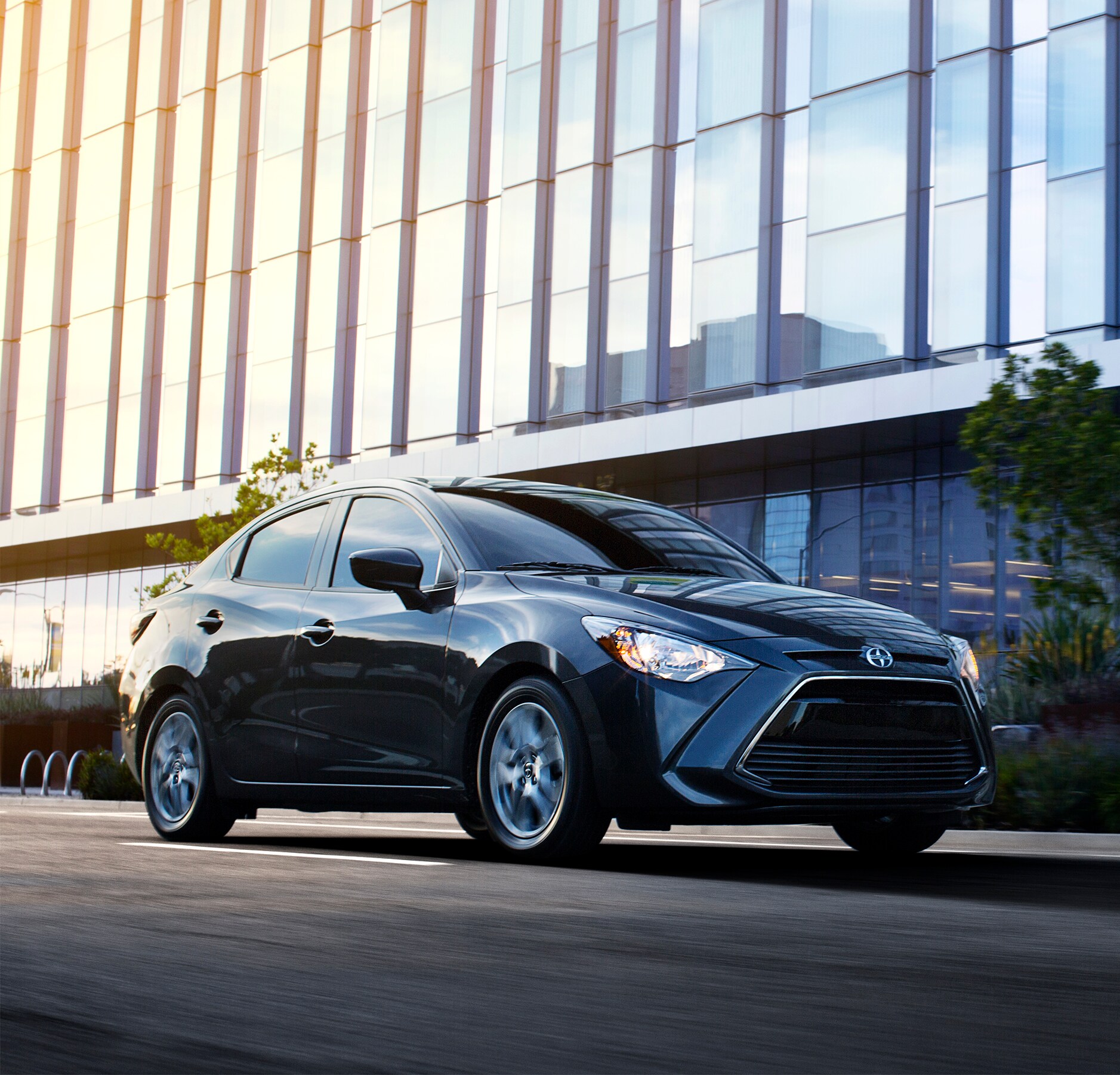 2016-Scion-iA-Base-Sedan-L01.png black Toyota Scion base sedan driving through city streets