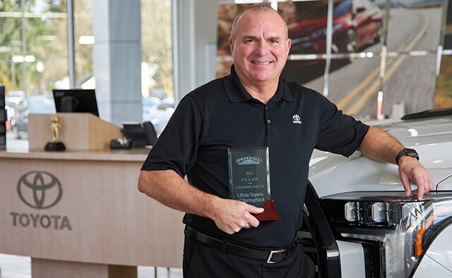 Lithia Toyota of Springfield manager standing next to a truck holding an award.