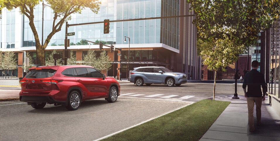 2020-Toyota-HighlanderHybrid-Platinum-SUV-L02 (2).png silver and red Toyota Highlander hybrid SUVs coming up to a stop light.