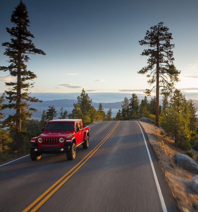 2023-Jeep-Gladiator-Rubicon-Truck.png red Jeep Gladiator truck driving through a forested area