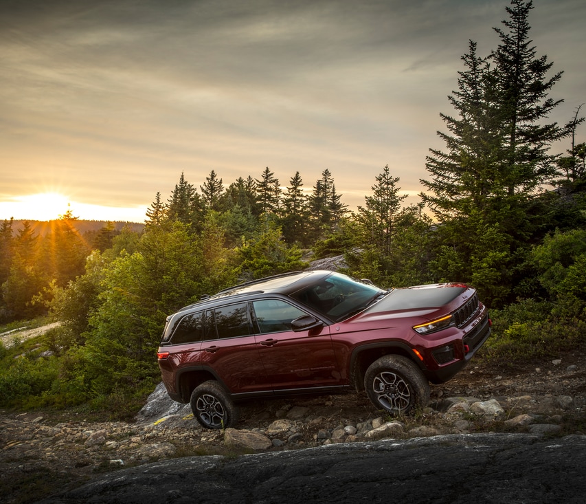 2022-Jeep-GrandCherokeeWL-Trailhawk-SUV.png dark red Jeep Grand Cherokee SUV climbing up the side of a river