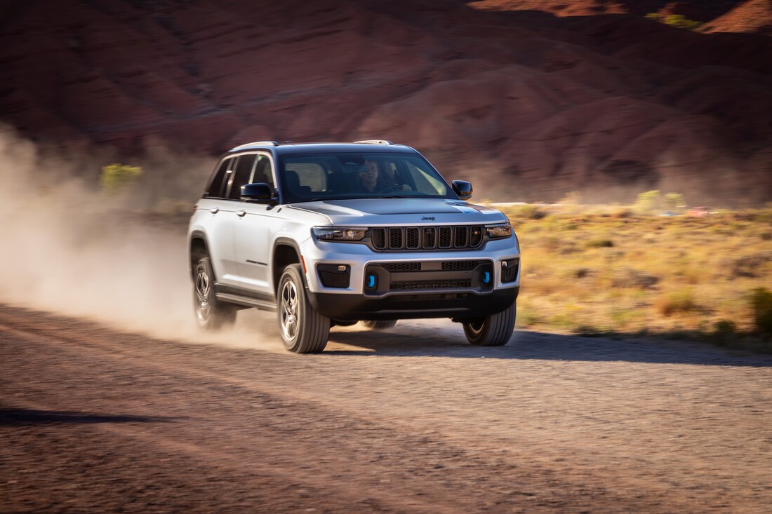 2022-Jeep-GrandCherokeeWL-4xe-Trailhawk-SUV-L02.png white Jeep Grand Cherokee SUV driving fast down a dusty road