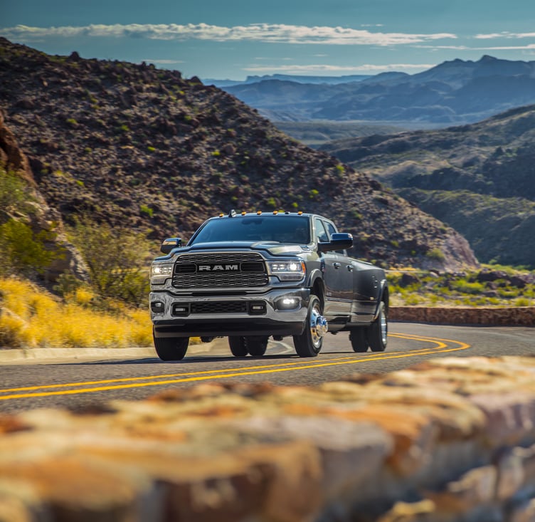 2021-RAM-3500-Limited-CrewCab-Truck-L07.png Ram 3500 truck driving up a road near mountains