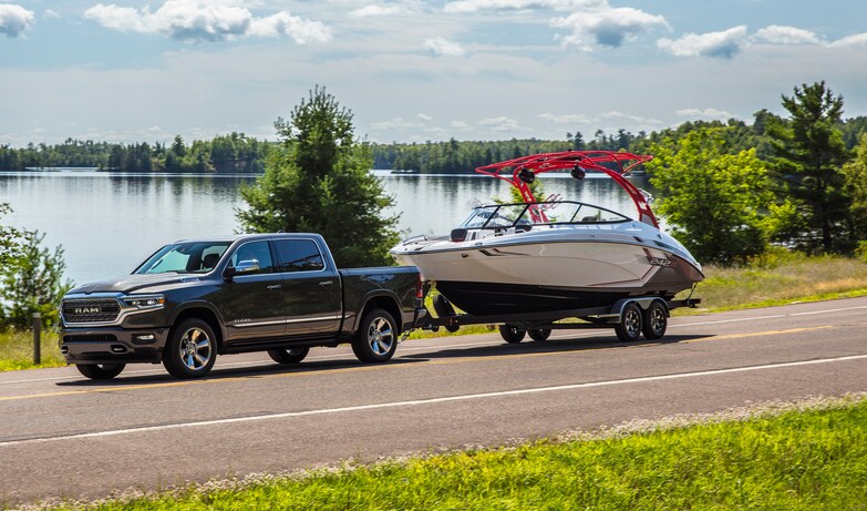 2022-RAM-1500-Limited-CrewCab-Truck-L07 (2).png black Ram 1500 truck towing a boat next to a lake