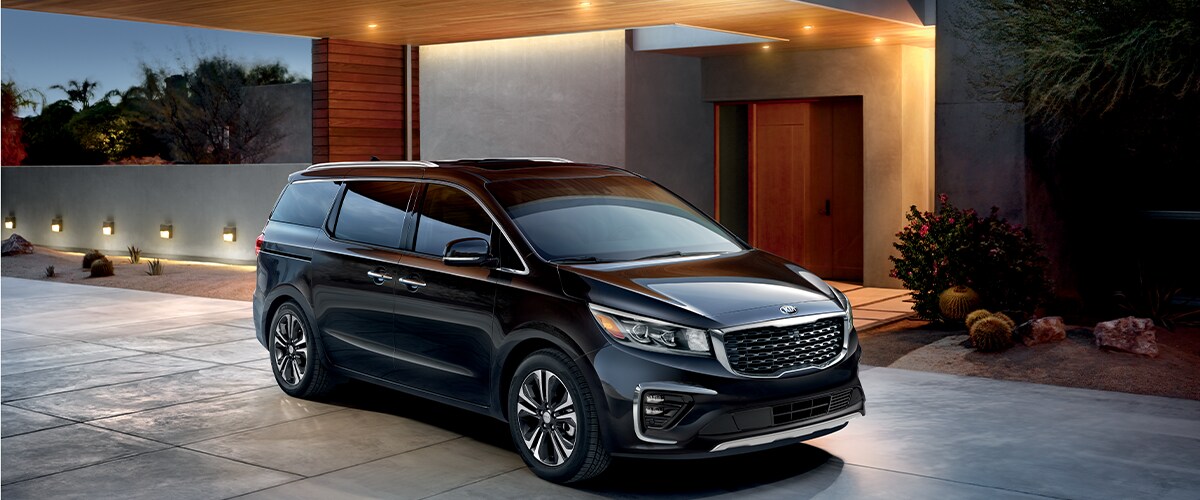 Black Kia Sedona parked in front of a house