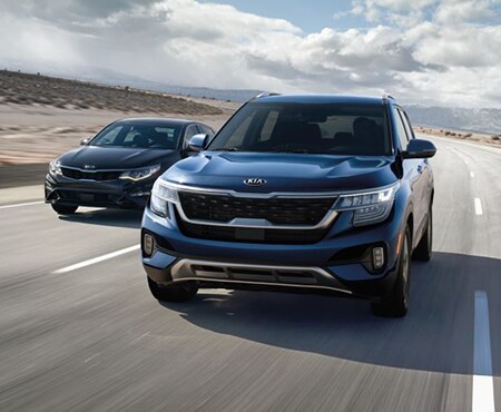Two vehicles driving down a road with the Kia Seltos in front