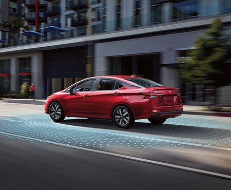 Red Nissan Versa driving in city