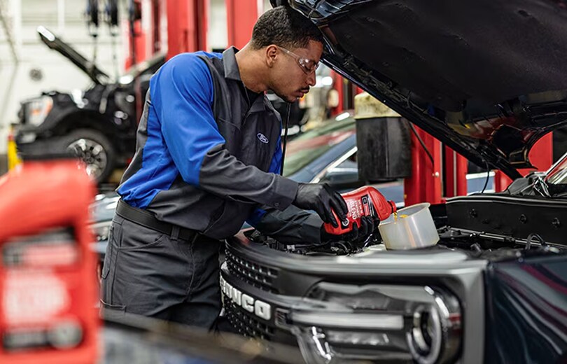 Maguire's Ford Technician pouring oil into a bronco