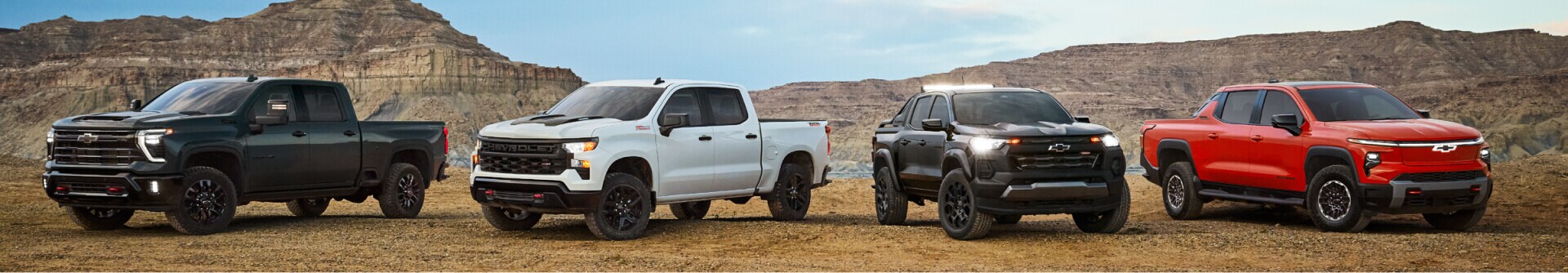 A lineup of Chevy trucks parked in a mountain clearing.