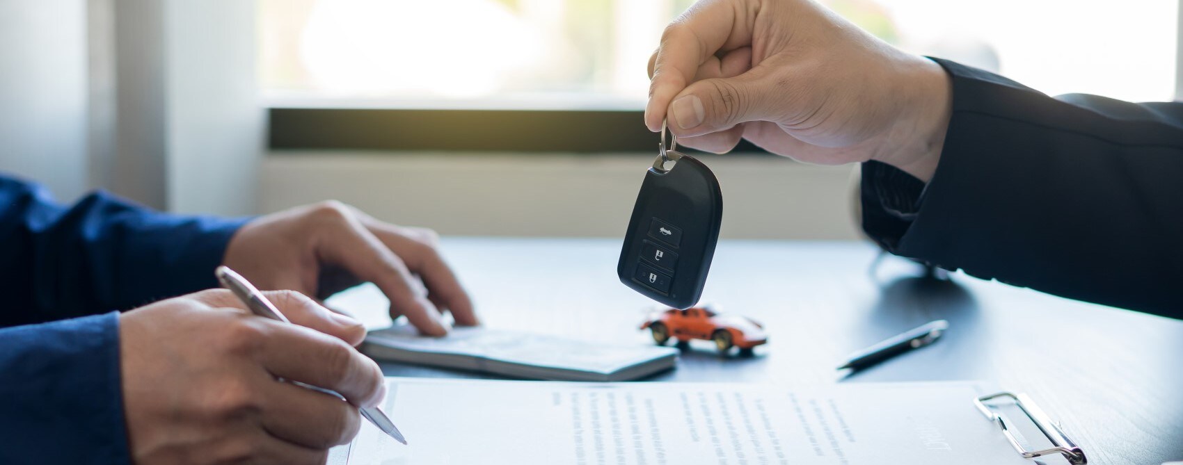 Signing car loan agreement buying a car handing keys over.jpg