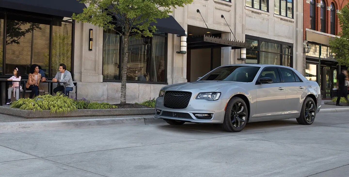 Brand new 2022 Chrysler 300 available today at AutoNation Chrysler Jeep West Chrysler 300 parked on city street next to two people at a cafe
