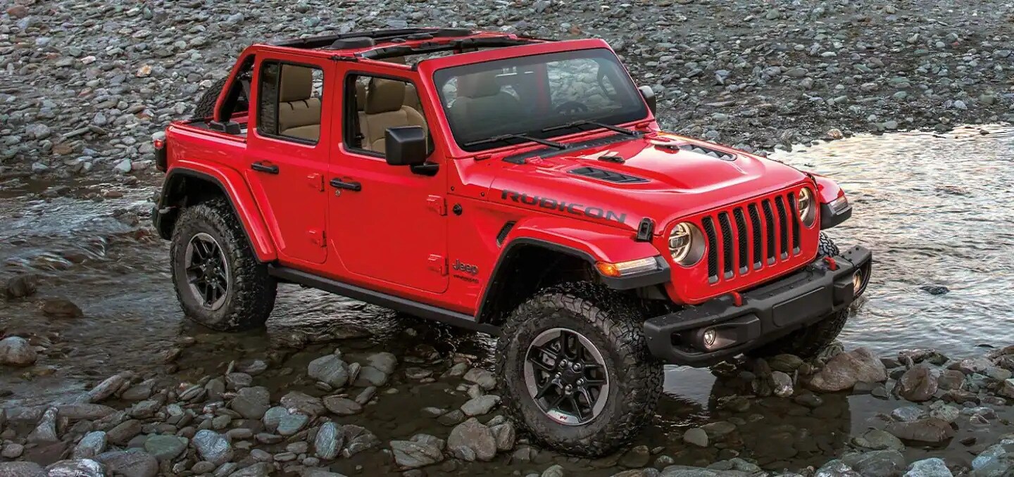 Brand new 2022 Jeep Wrangler available today at AutoNation Chrysler Dodge Jeep Ram Valencia Jeep Wrangler parked in a stream with it's back wheels touching the water