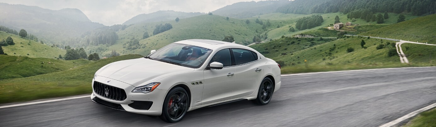 white 2019 Maserati Quattroporte from dirver side view driving through green hills