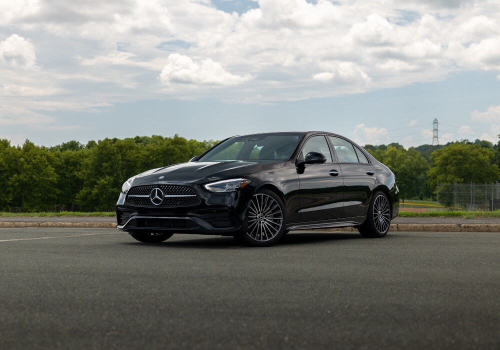 2026-mercedes-benz-c-class-for-sale.png Black 2026 Mercedes-Benz C-Class parked on a paved lot with trees in the backgrounf