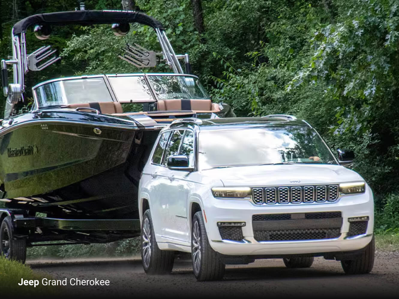 2025 Jeep Grand Cherokee Summit in two tone Bright White and black towing a large boat