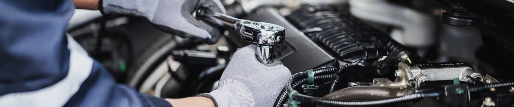 Close-up image of a mechanic working on the engine of a Chevy vehicle