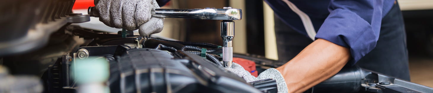 A service technician working under the hood of a vehicle