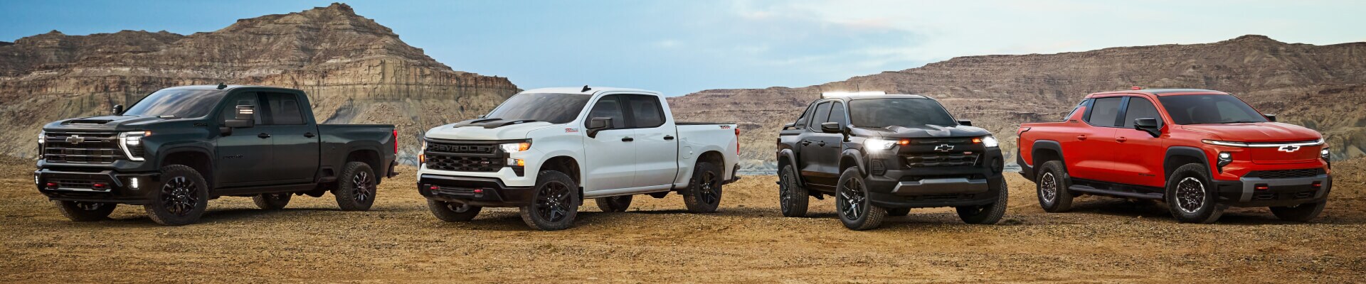 Chevy Silverado 1500, Silverado 2500, Silverado EV, and Colorado Crew Cab parked in front of a desert landscape