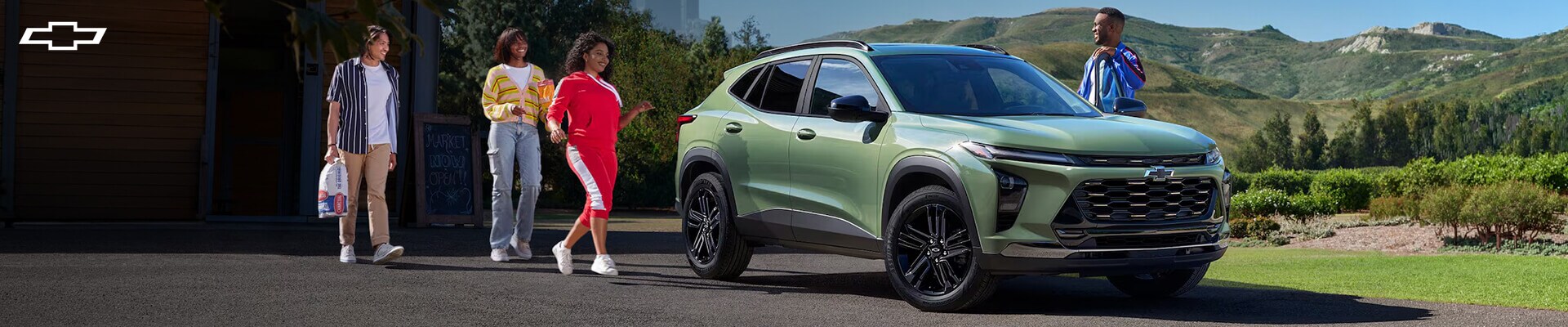 Two couples approaching a green 2026 Chevy Trax