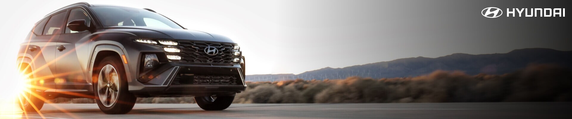 2026 Hyundai Tucson driving on the road with the sun glimmering off the back tire