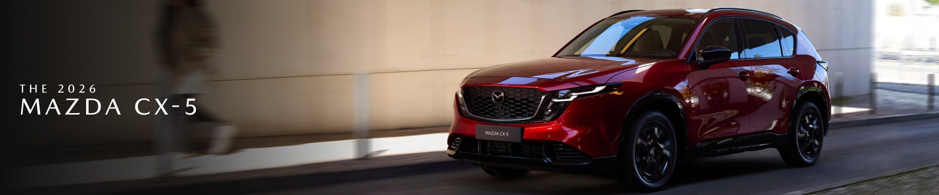 2026 Mazda CX-5 in Red driving in front of a stone wall