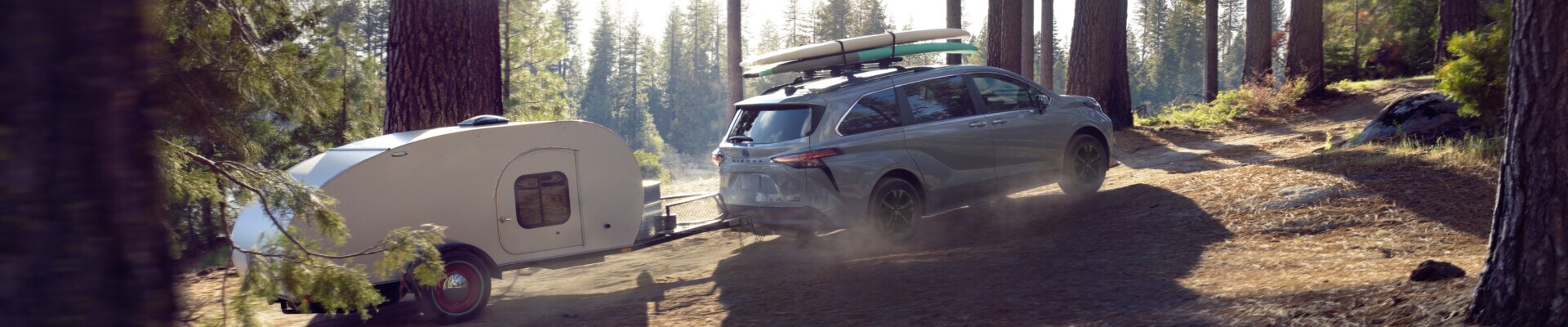 Toyota Sienna Woodland Edition in Silver Cement towing a trailer in the woods near Weymouth, MA.