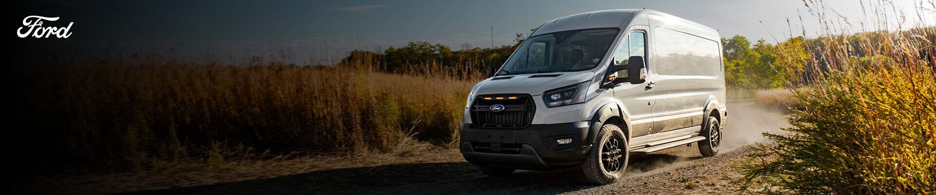 Ford Transit Trail Cargo Van High Roof exterior in Avalanche Gray kicking up dust on a rural dirt road.