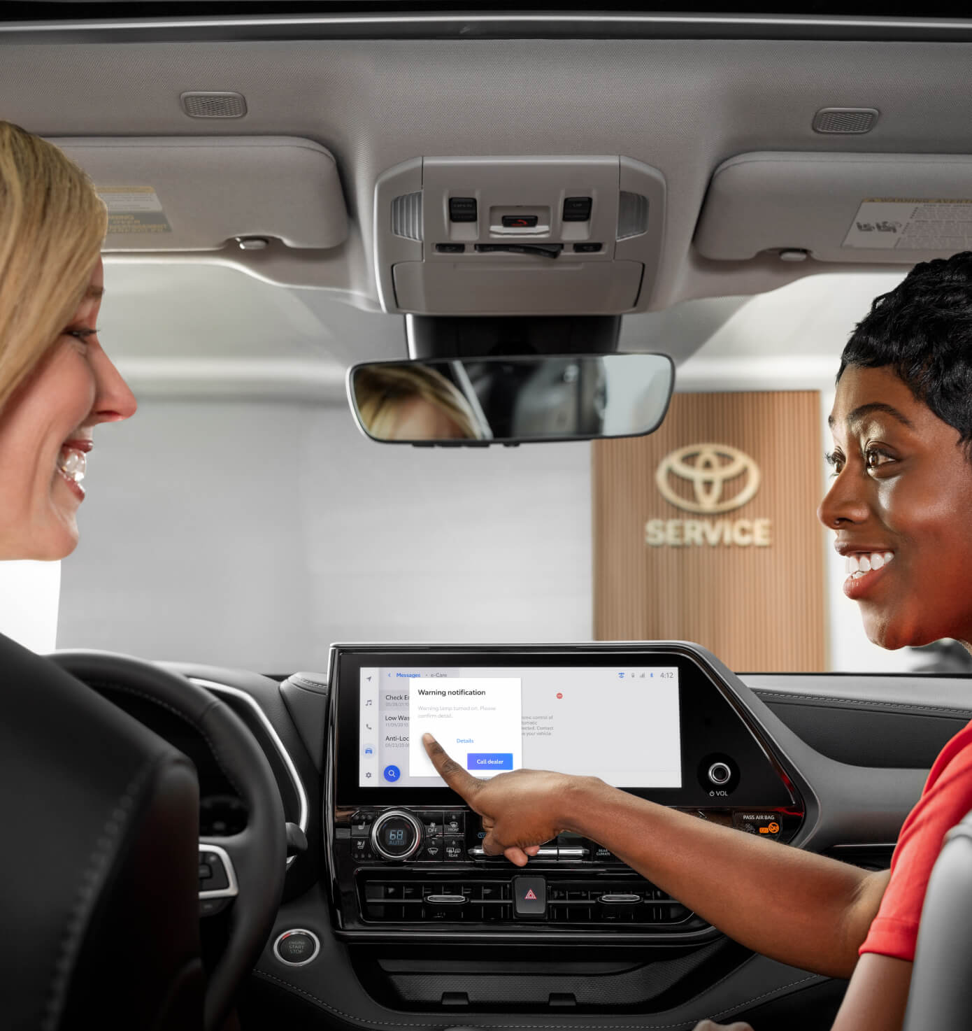 Toyota owner being helped with the display in her new car by a Toyota service staff member