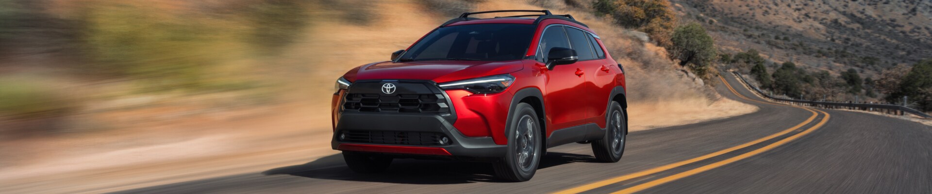 2026 Toyota Corolla Cross XLE AWD in Soul Red Crystal Driving on the highway through a natural landscape