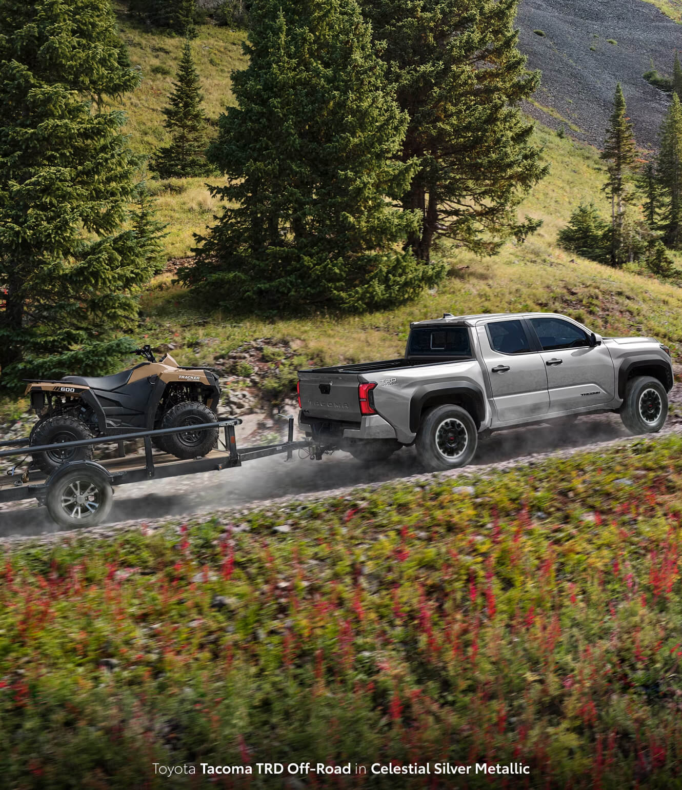 Toyota Tacoma TRD Off-Road in Celestial Silver Metallic towing an ATV uphill through a forest