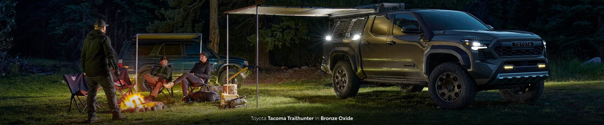 Family camping alongside their Toyota Tacoma Trailhunter in Bronze Oxide
