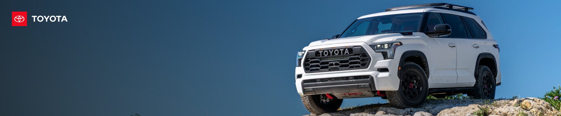 Front-three-quarter view of a 2026 White Toyota Sequoia TRD Pro parked on a rocky outcrop.