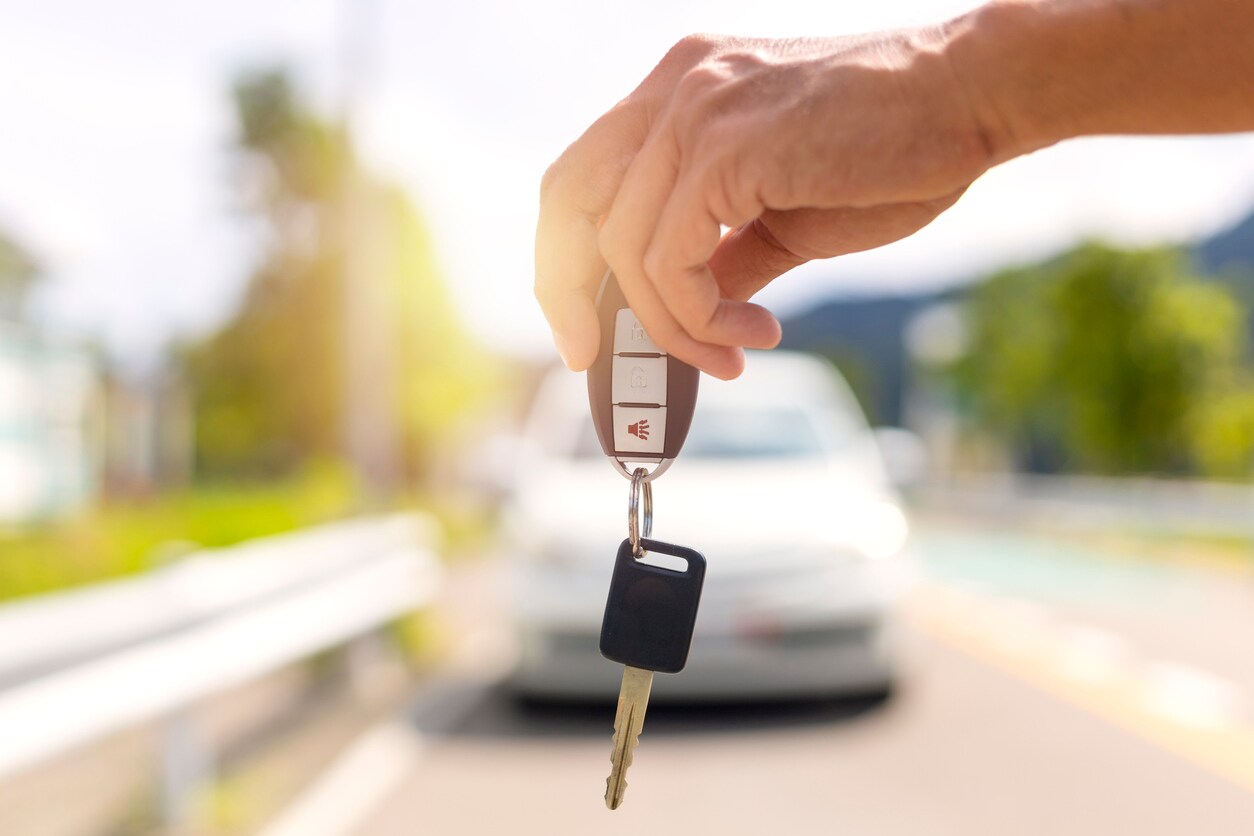hands holding a pair of car keys in front of car
