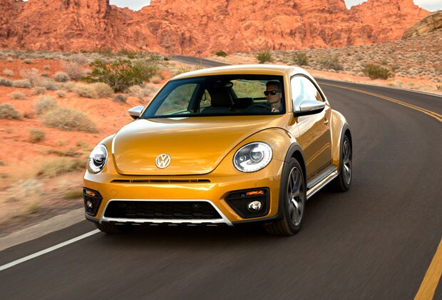 Yellow VW Beetle driving down a road