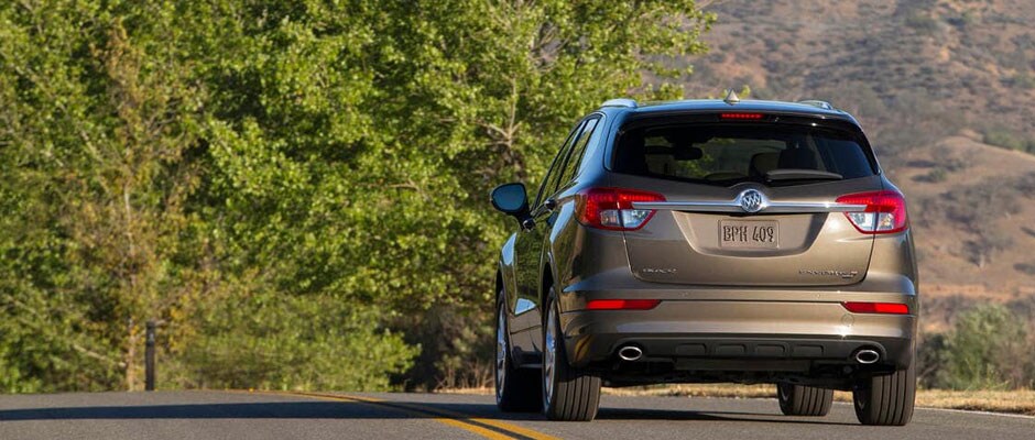 Bronze Buick Envision driving down a road