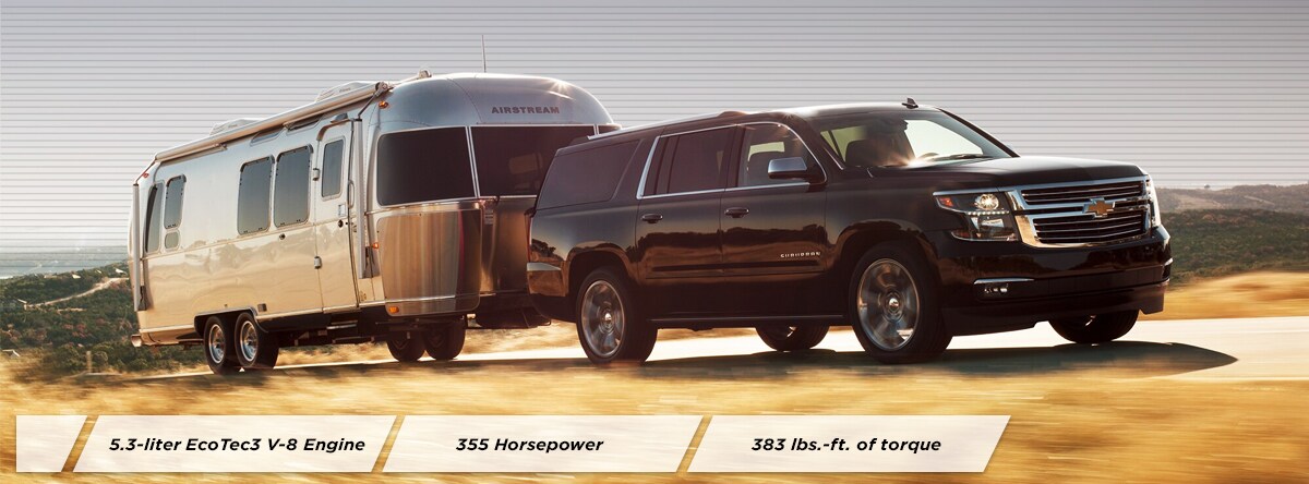 2019 Black Chevy Suburban Hauling a camper down an open road