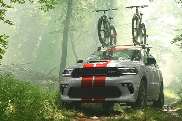 Dodge Durango dirivng through rough terrain in forrest with bikes on the roof