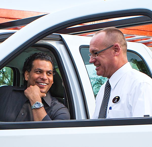 Car salesman greeting customer seated in truck