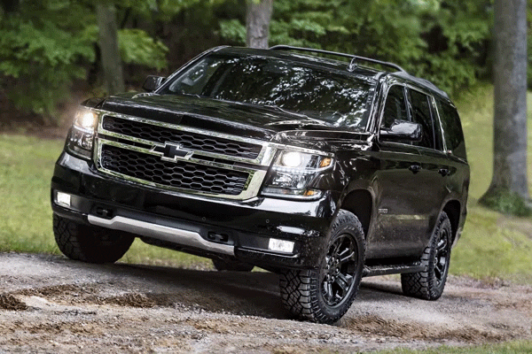 2019 Chevy Tahoe Premiere Plus Black driving down the street in a wooded area
