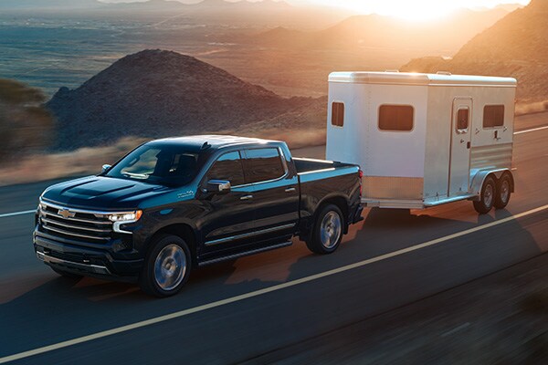 Chevy Silverado 1500 driving down the road hauling a trailer