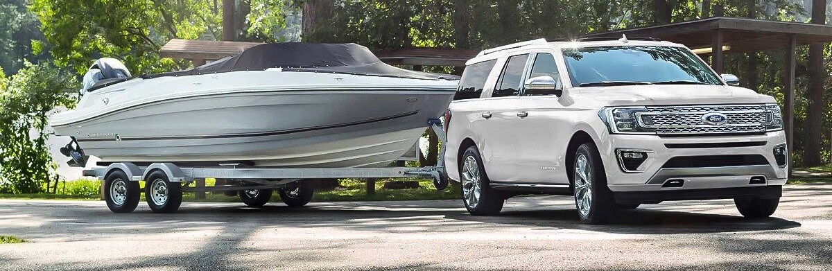 2019 Ford Expedition towing a boat in a wooded area