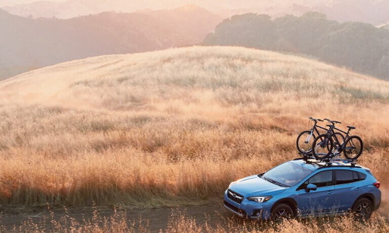 2020 Subaru Crosstrek in blue driving up dirt road in the in a open field view from above