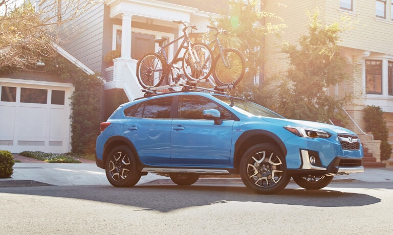 2020 Subaru Crosstrek in blue with loaded bike rack leaving driveway